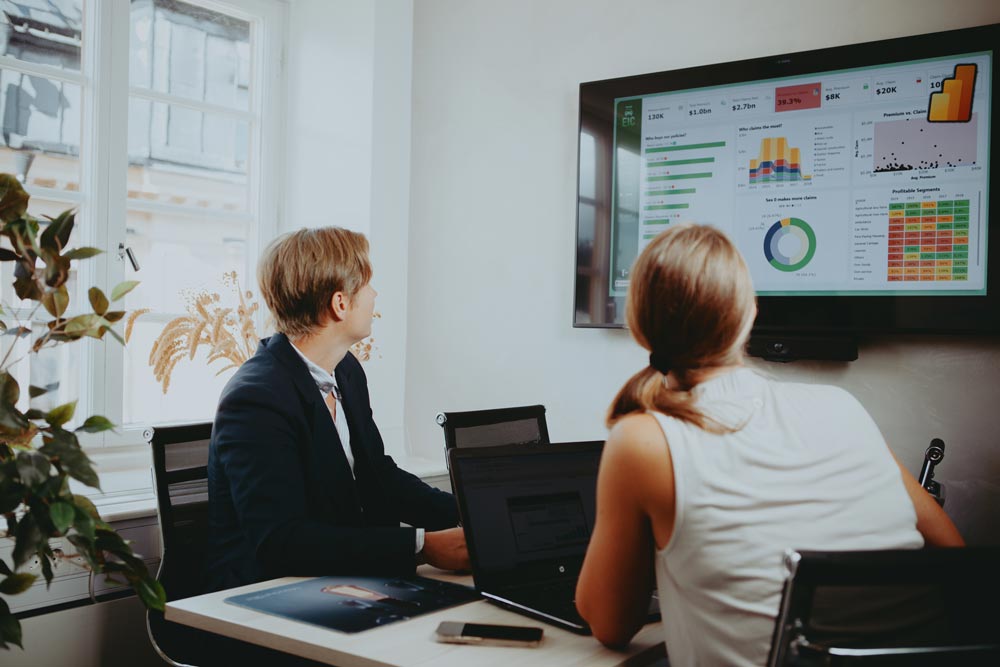 Två kollegor som kollar på en skärm med statistik